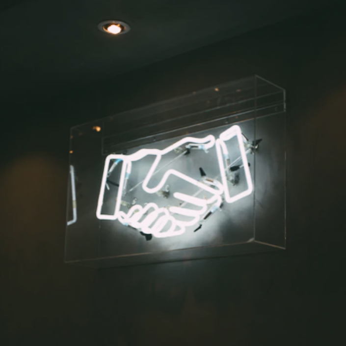 Neon przedstawiający uścisk dłoni