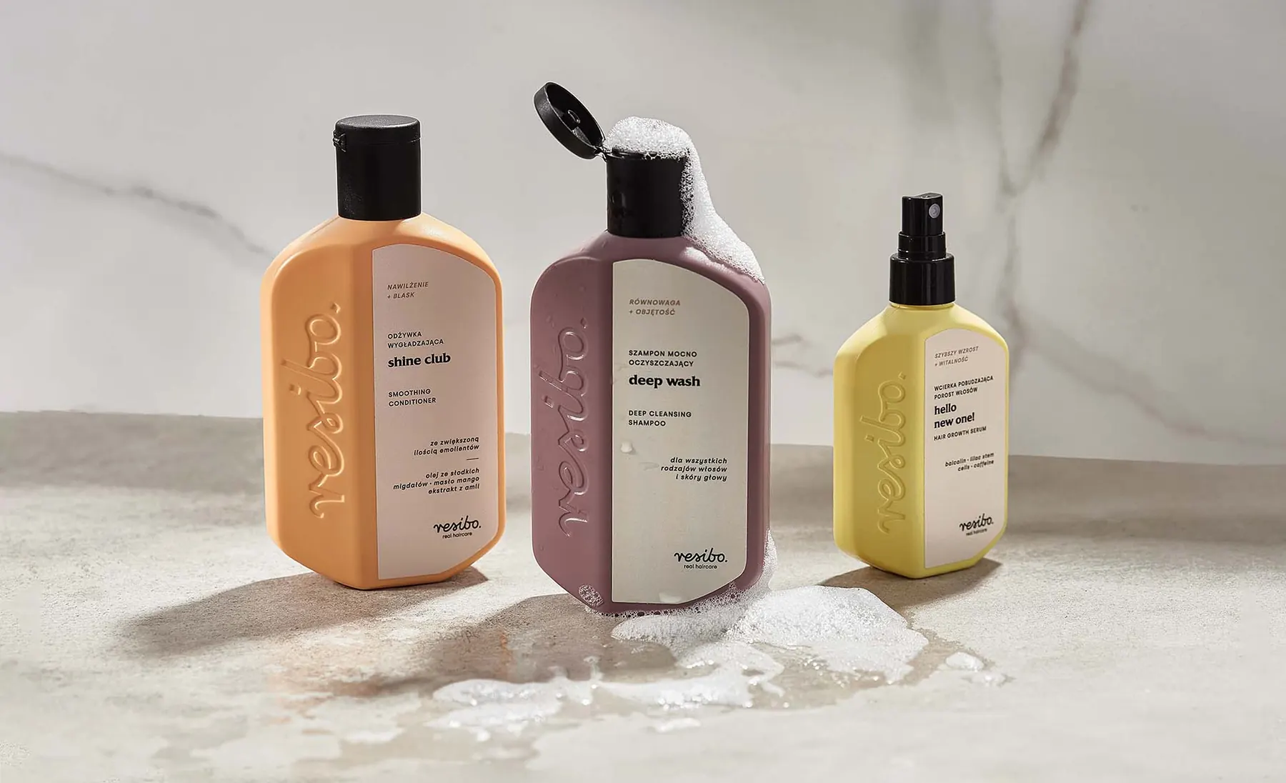 Four Resibo Hair Care bottles on marble